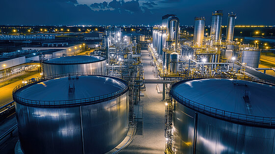 Industrial facility at night with large storage tanks and illuminated structures.