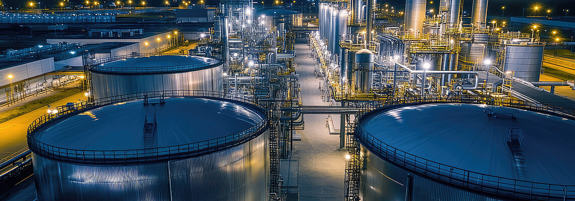 Industrial facility at night with large storage tanks and illuminated structures.